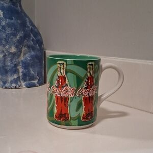 Coca-Cola Mug with Red Bottles and Green Background